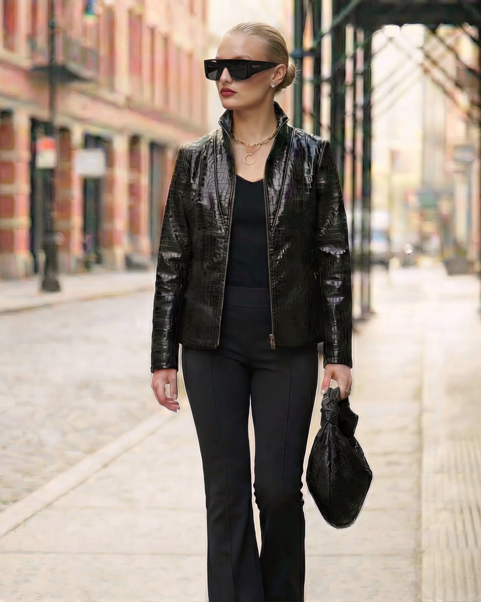 Woman wearing a black embossed jacket and black pants on a city street