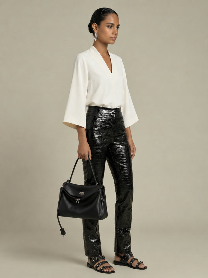 Three-quarter view of the Pearl Waverly flutter sleeve top styled with black croc embossed pants.